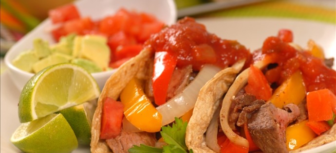 Fajitas with a variety of condiments and limes